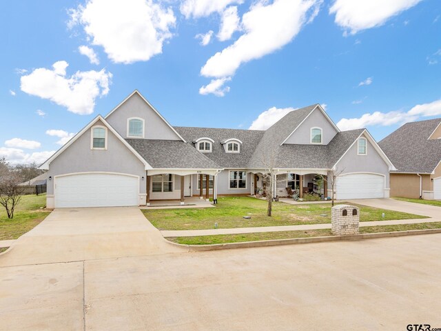 view of front facade with a shingled roof, a front lawn, concrete driveway, and stucco siding