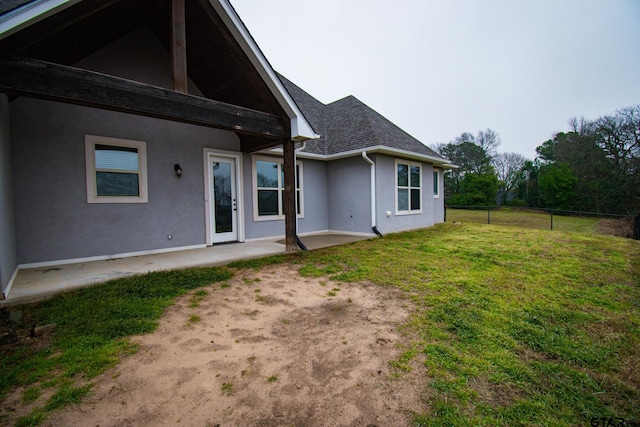 back of property with a patio, fence, a yard, roof with shingles, and stucco siding