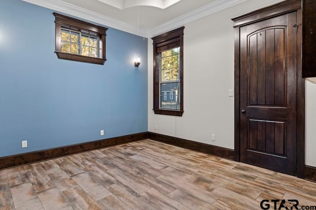 empty room featuring a healthy amount of sunlight, light hardwood / wood-style flooring, and crown molding