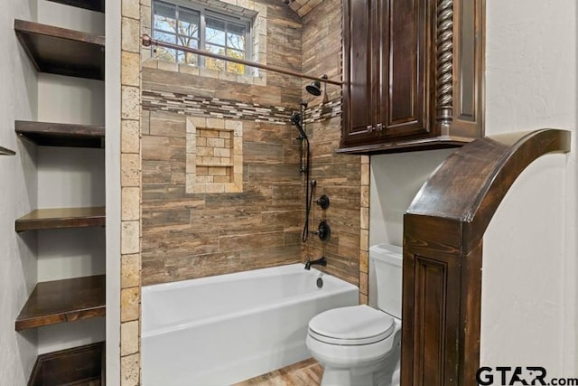 bathroom with hardwood / wood-style flooring, tiled shower / bath, and toilet