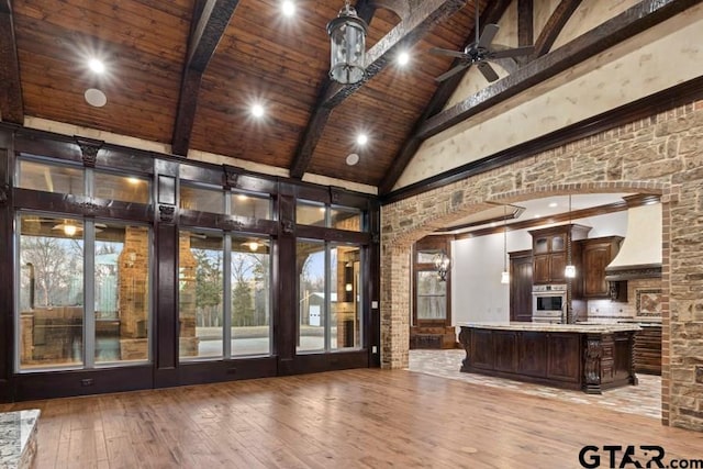 interior space with light hardwood / wood-style floors, beamed ceiling, custom exhaust hood, wood ceiling, and stainless steel oven