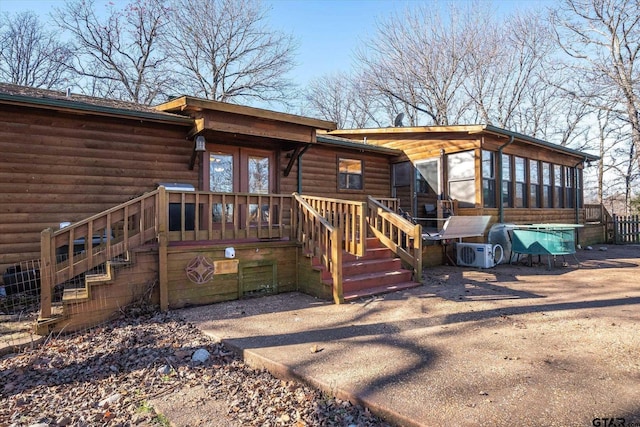 view of front facade featuring faux log siding, stairs, a sunroom, and a wooden deck