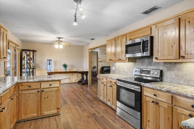 kitchen featuring visible vents, a textured ceiling, dark wood finished floors, stainless steel appliances, and a peninsula