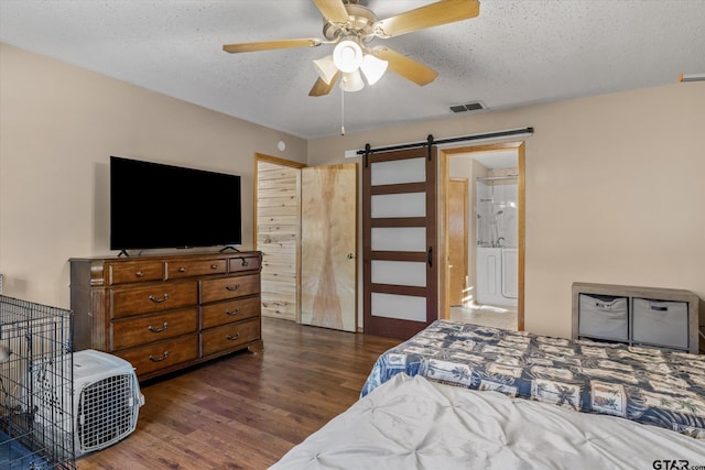 bedroom featuring visible vents, ceiling fan, dark wood-type flooring, a textured ceiling, and a barn door