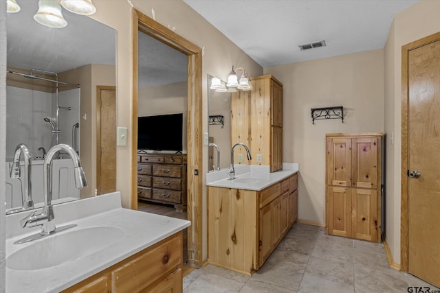 bathroom with a sink, visible vents, a shower, and two vanities