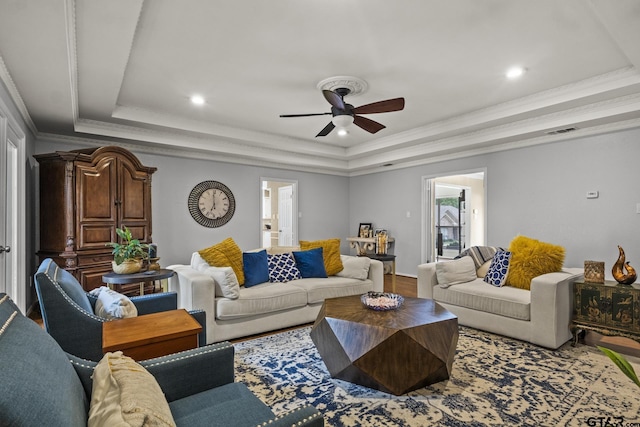 living room featuring ceiling fan, hardwood / wood-style floors, a tray ceiling, and ornamental molding