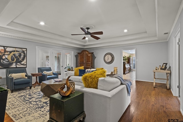 living room with ceiling fan, a tray ceiling, and dark hardwood / wood-style flooring