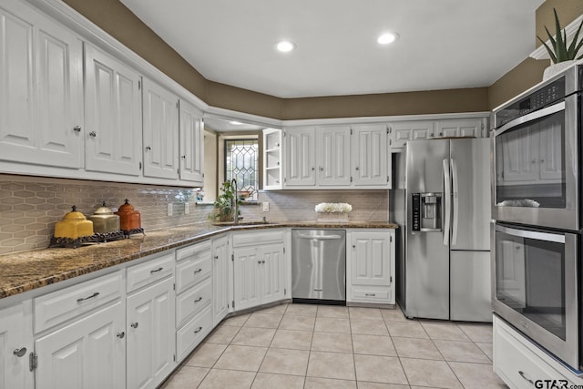 kitchen with light tile patterned flooring, white cabinetry, stainless steel appliances, and dark stone countertops