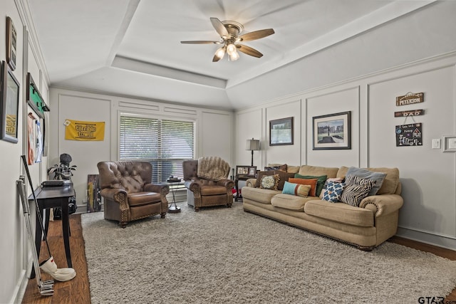 living room with ceiling fan, hardwood / wood-style floors, a tray ceiling, and ornamental molding