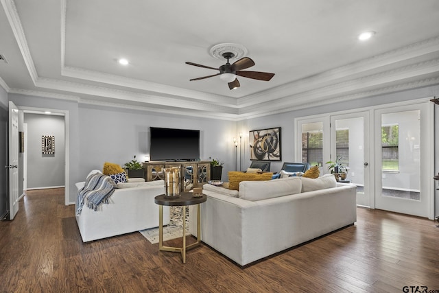 living room featuring dark wood-type flooring, ceiling fan, crown molding, and a tray ceiling