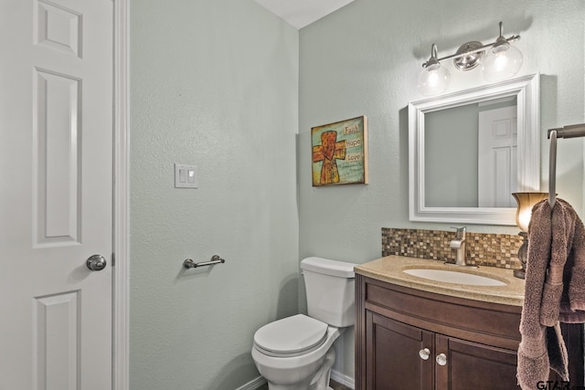 bathroom with toilet, decorative backsplash, and vanity