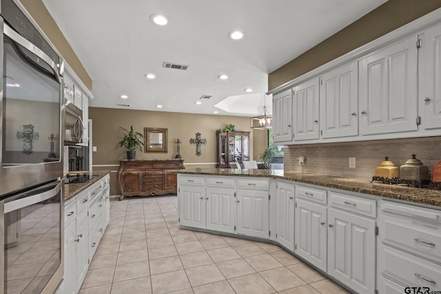 kitchen featuring a skylight, dark stone counters, white cabinetry, and stainless steel appliances