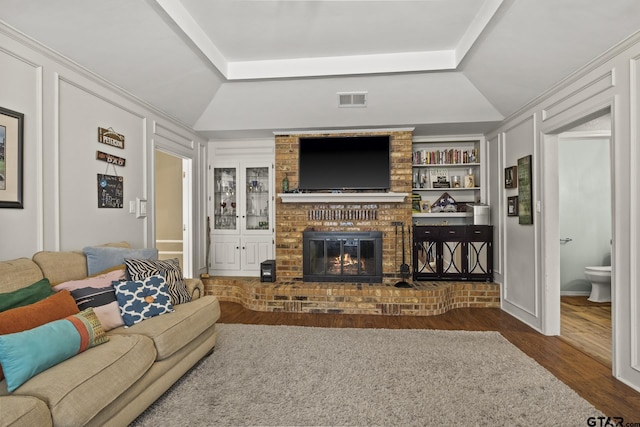 living room featuring a fireplace, built in features, and dark hardwood / wood-style floors