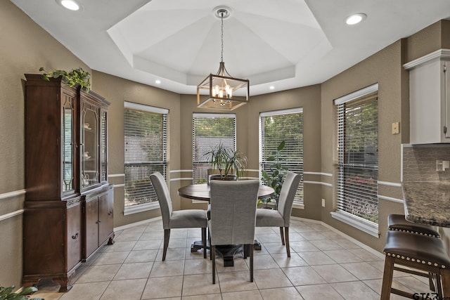 tiled dining room featuring a raised ceiling and a chandelier