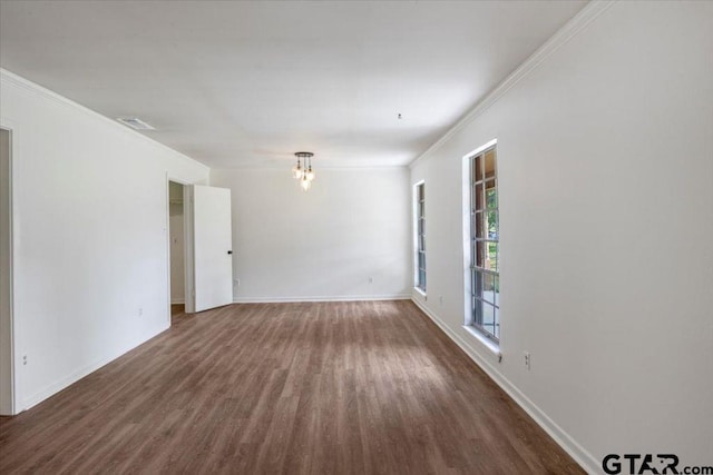 spare room featuring visible vents, ornamental molding, baseboards, and wood finished floors