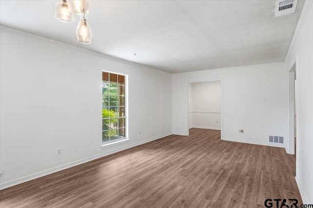 unfurnished room with baseboards, ornamental molding, wood finished floors, and visible vents