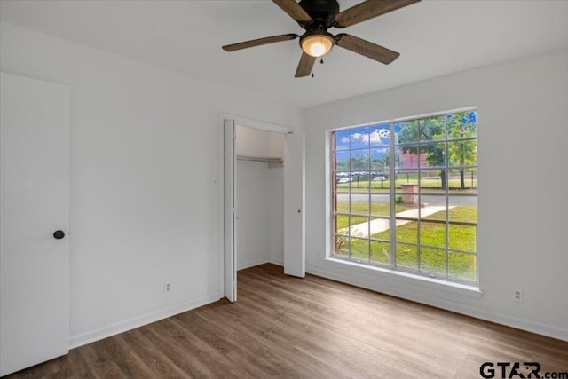 unfurnished bedroom with baseboards, a ceiling fan, wood finished floors, and a closet