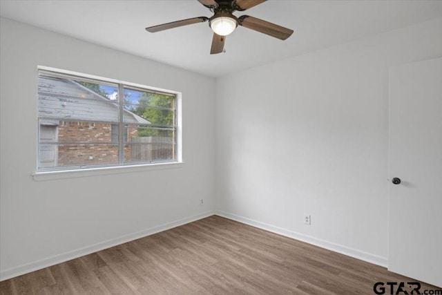 spare room with baseboards, ceiling fan, and wood finished floors