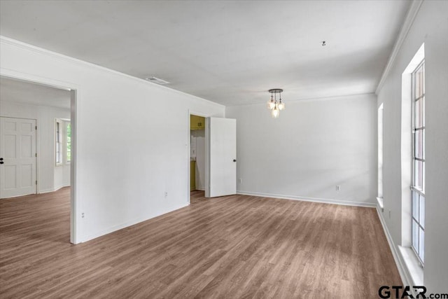 unfurnished room with baseboards, ornamental molding, wood finished floors, and visible vents