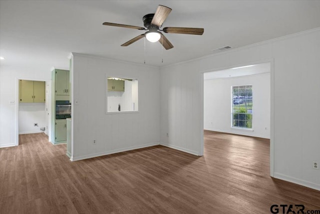 spare room with crown molding, a ceiling fan, wood finished floors, and visible vents