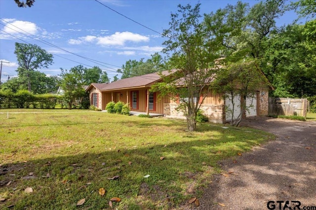 ranch-style house featuring board and batten siding, driveway, a garage, fence, and a front lawn