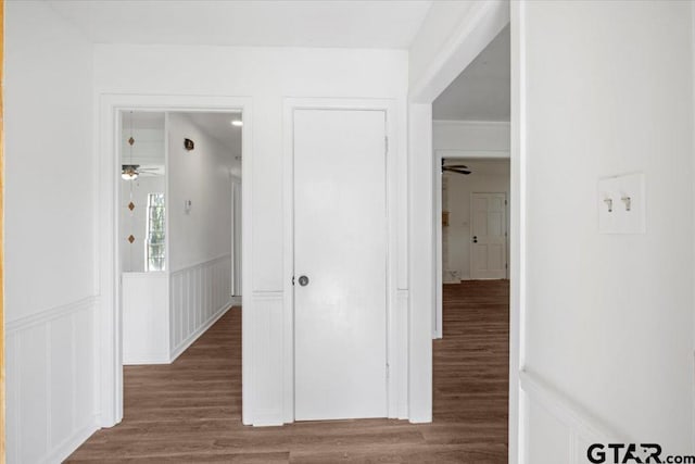 corridor featuring a wainscoted wall and wood finished floors