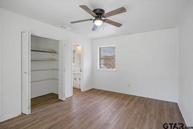 unfurnished bedroom featuring visible vents, a closet, wood finished floors, baseboards, and ceiling fan