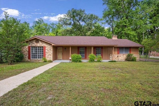 ranch-style home with roof with shingles, brick siding, board and batten siding, a front yard, and a chimney