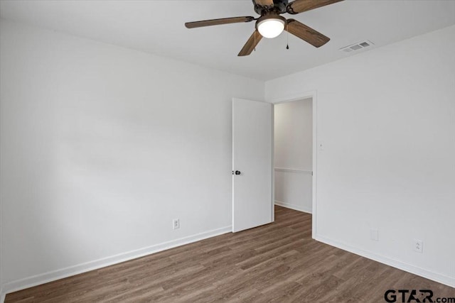 empty room featuring baseboards, ceiling fan, visible vents, and wood finished floors