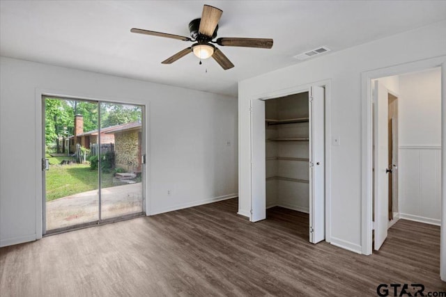 unfurnished bedroom with baseboards, access to outside, wood finished floors, and visible vents