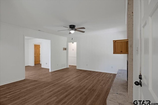 empty room featuring crown molding, dark wood-style flooring, ceiling fan, and baseboards