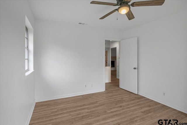 unfurnished room featuring baseboards, ceiling fan, visible vents, and wood finished floors