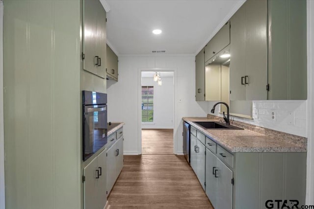 kitchen featuring visible vents, wood finished floors, a sink, light countertops, and oven