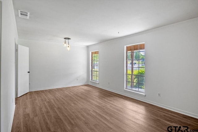 spare room with crown molding, baseboards, and wood finished floors
