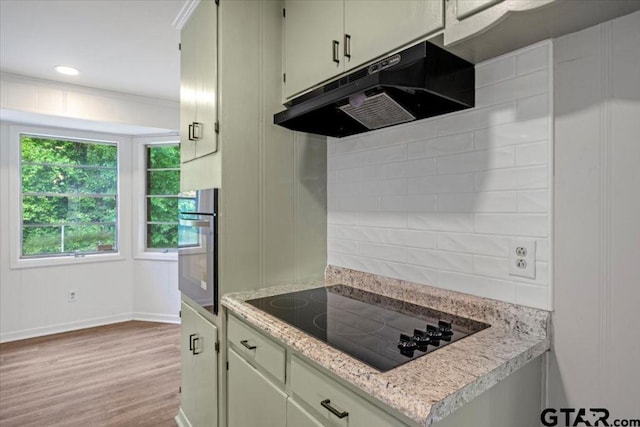 kitchen featuring baseboards, stainless steel oven, black electric stovetop, under cabinet range hood, and light wood-style flooring