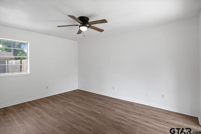empty room featuring ceiling fan, dark wood finished floors, and baseboards
