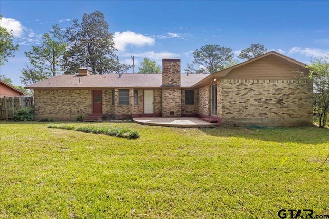 back of house featuring a chimney, a patio area, brick siding, fence, and a yard