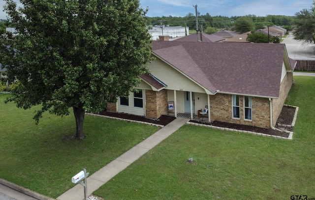 ranch-style home with a front lawn, roof with shingles, brick siding, and covered porch