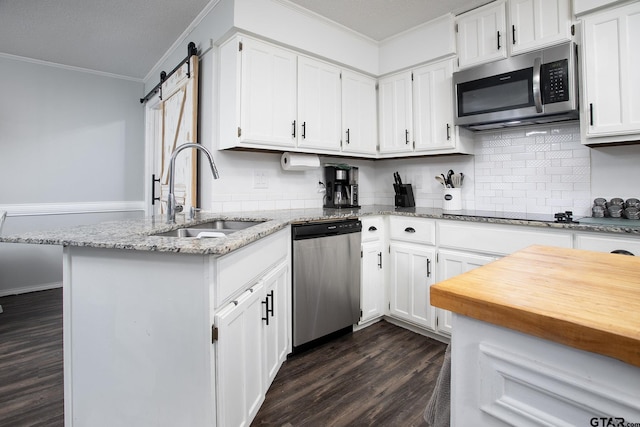 kitchen with a sink, crown molding, dark wood finished floors, light stone countertops, and appliances with stainless steel finishes