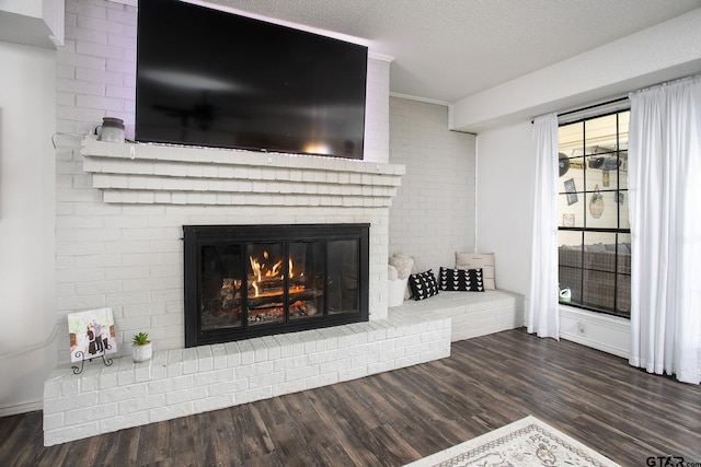 room details with a textured ceiling, wood finished floors, and a brick fireplace