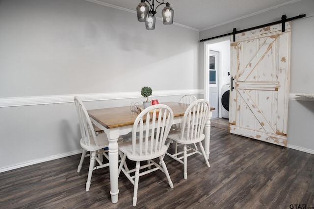 dining area featuring a notable chandelier, a barn door, ornamental molding, washer / dryer, and dark wood-type flooring