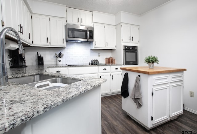 kitchen featuring black oven, dark wood-style floors, a sink, and stainless steel microwave