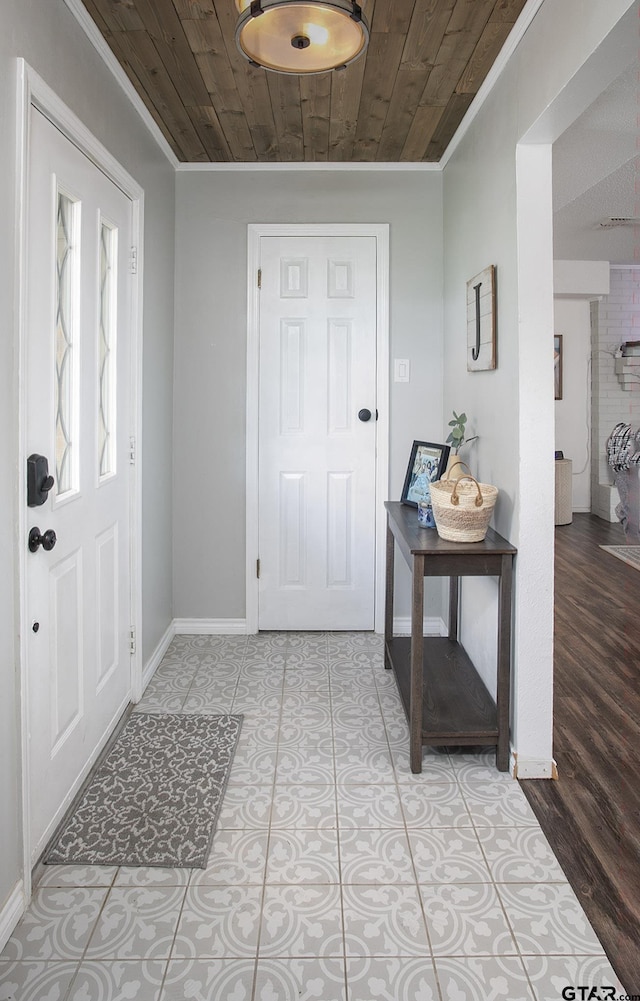 entryway with wooden ceiling, ornamental molding, and baseboards