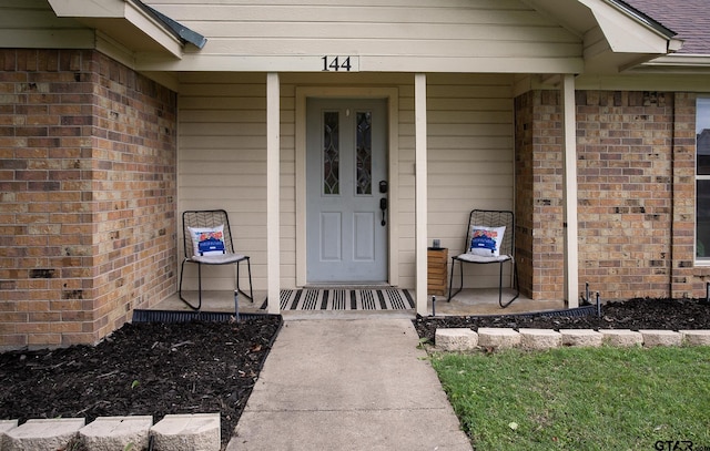 property entrance with brick siding and covered porch