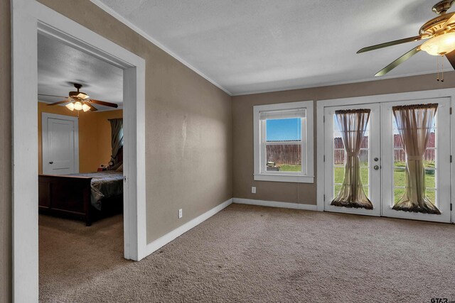 carpeted empty room featuring french doors, a ceiling fan, crown molding, and baseboards