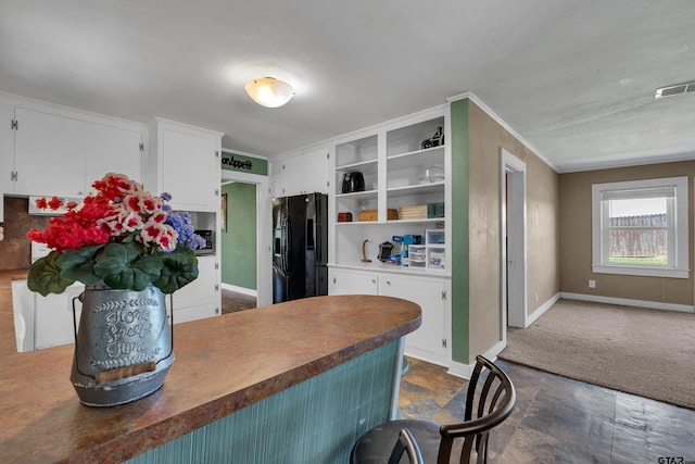 kitchen featuring visible vents, black fridge, open shelves, white cabinets, and baseboards