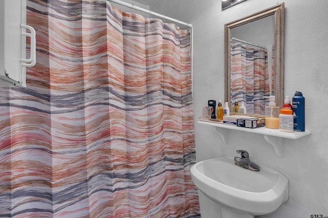 bathroom with a shower with shower curtain and a sink