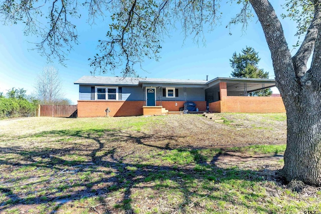 view of front of property with an attached carport, brick siding, a front yard, and fence