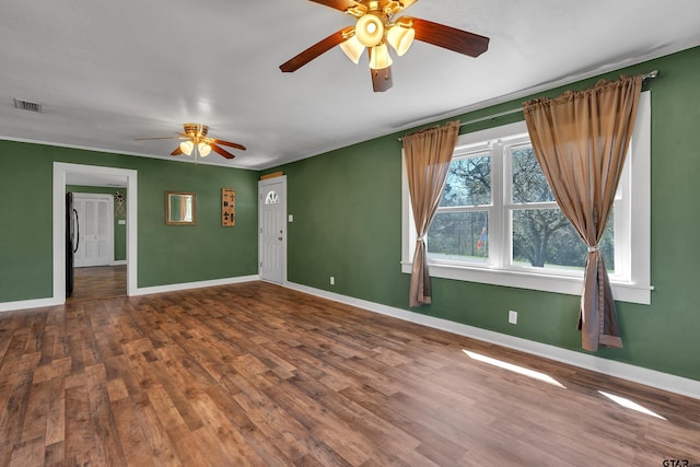 empty room featuring visible vents, baseboards, wood finished floors, and crown molding