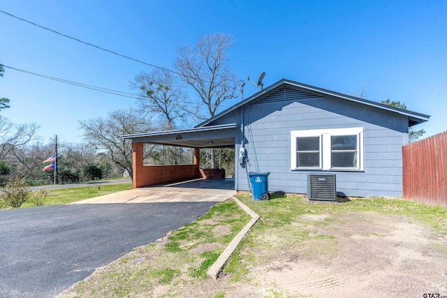 view of home's exterior with central air condition unit, an attached carport, driveway, and fence